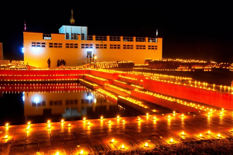 A grand building adorned with numerous glowing diyas in its foreground.